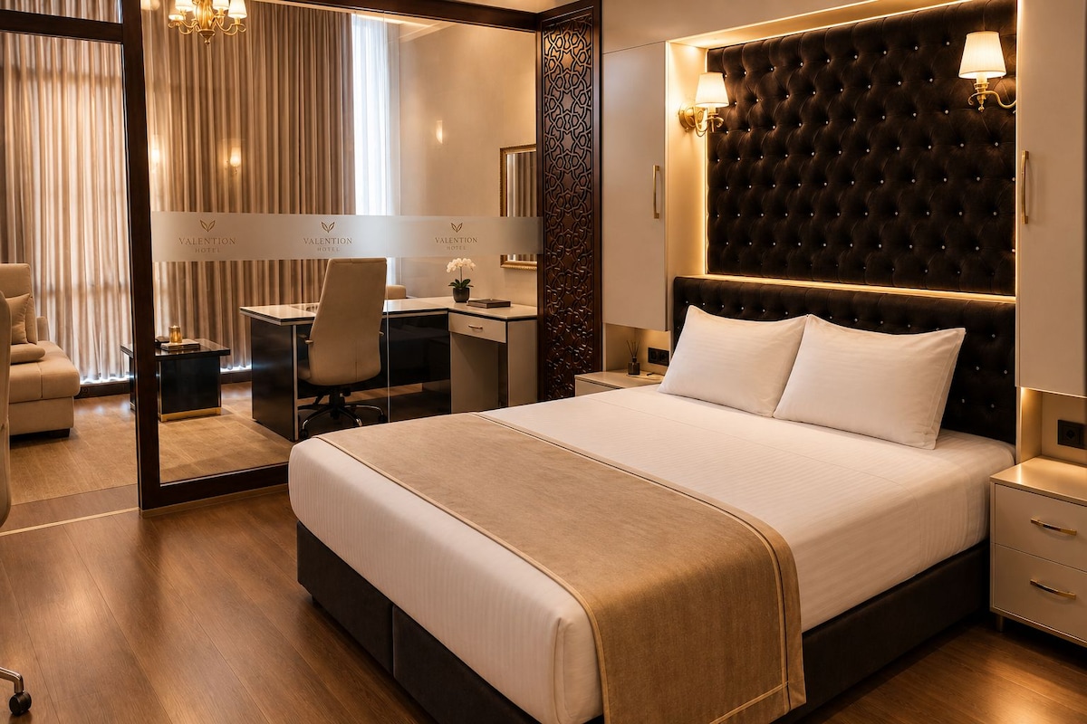 Una habitación de hotel con una cama grande, un escritorio, una silla y un espejo.