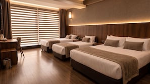 Una habitación de hotel con dos camas, un escritorio y un ventanal grande con persianas.