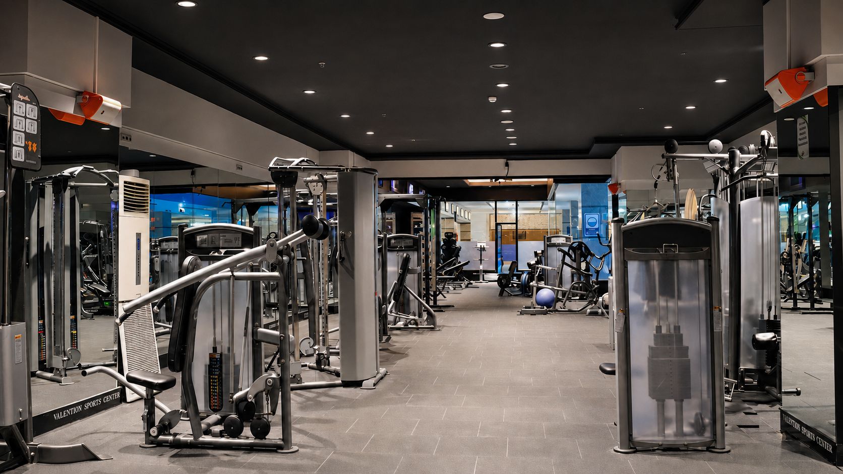 Ett gym med olika typer av träningsutrustning, inklusive styrketräningsmaskiner och lösa vikter.