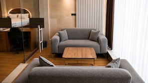 A modern living room with a sofa, a coffee table, and a desk with a chair.