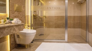 A modern bathroom with a toilet, a shower, and a vanity with a mirror.