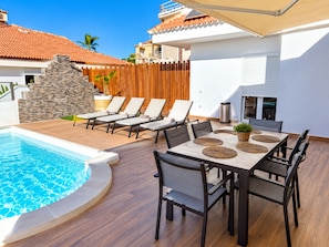 A poolside area with lounge chairs, a dining table, and a stone wall. - Stunning Costa Adeje Villa: 3BD, Private Pool, Terrace & AC (Costa Adeje)
