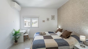 A bedroom with a bed, a desk, a chair, a potted plant, and a window. - Stunning Costa Adeje Villa: 3BD, Private Pool, Terrace & AC (Costa Adeje)