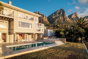 Ein modernes, zweistöckiges Haus mit Swimmingpool, Außenbereich und Bergblick.