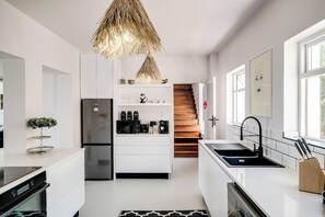 Eine moderne Küche mit weißen Schränken, einem Edelstahlkühlschrank, einer eingebauten Mikrowelle und einem schwarzen Spülbecken.