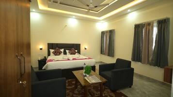 A hotel room with a bed, two armchairs, a coffee table, and a window with curtains.