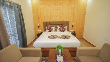 A hotel room with a large bed, two bedside tables, a coffee table with a plant, and two armchairs.