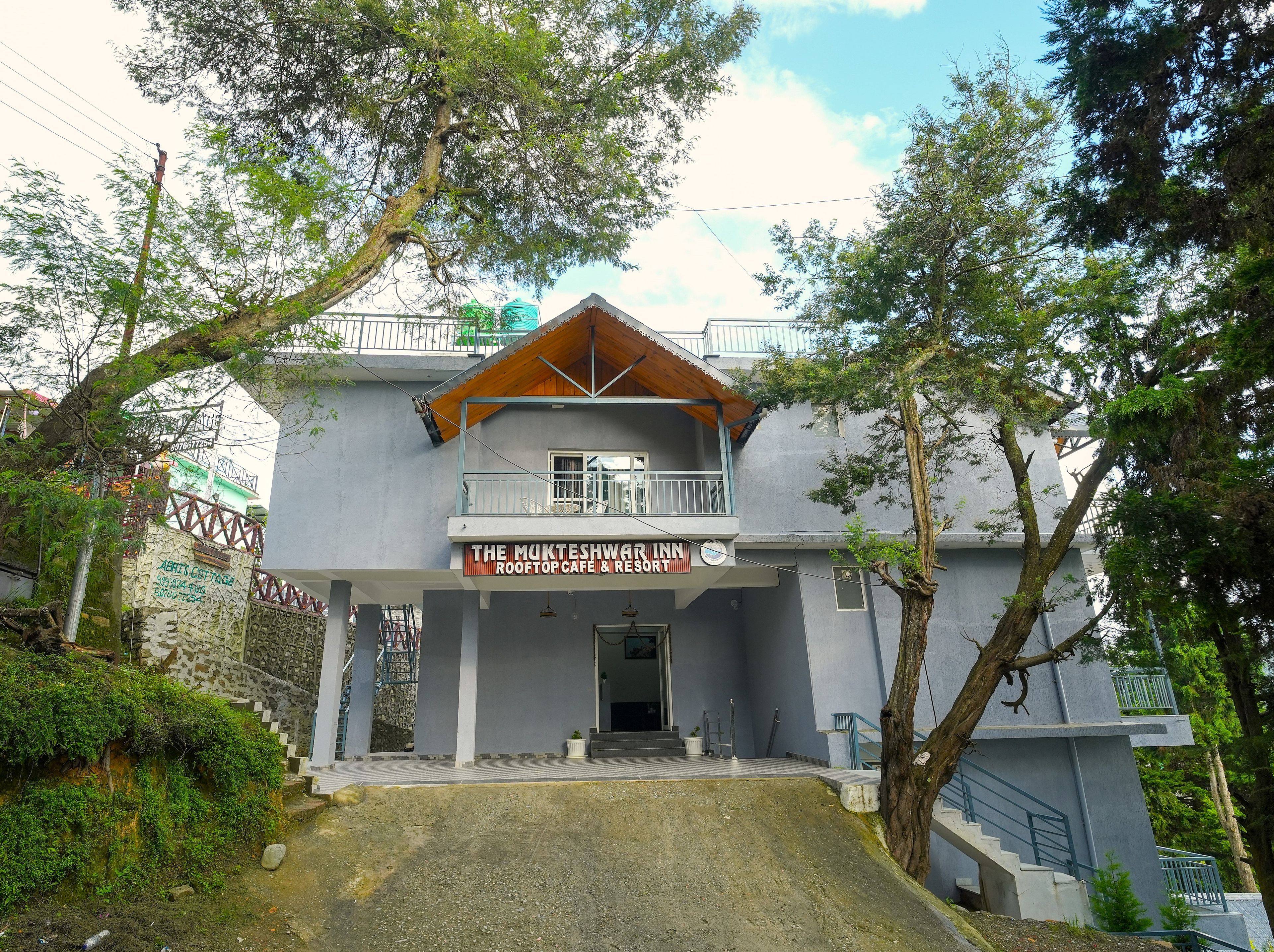 A two-story building with a sign for 'The Mukteshwari Inn Rooftop Cafe & Resort'.