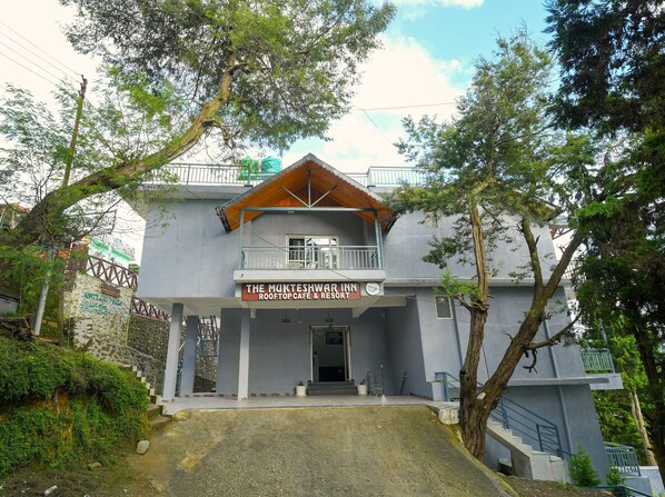 A two-story building with a sign for 'The Mukteshwari Inn Rooftop Cafe & Resort'.