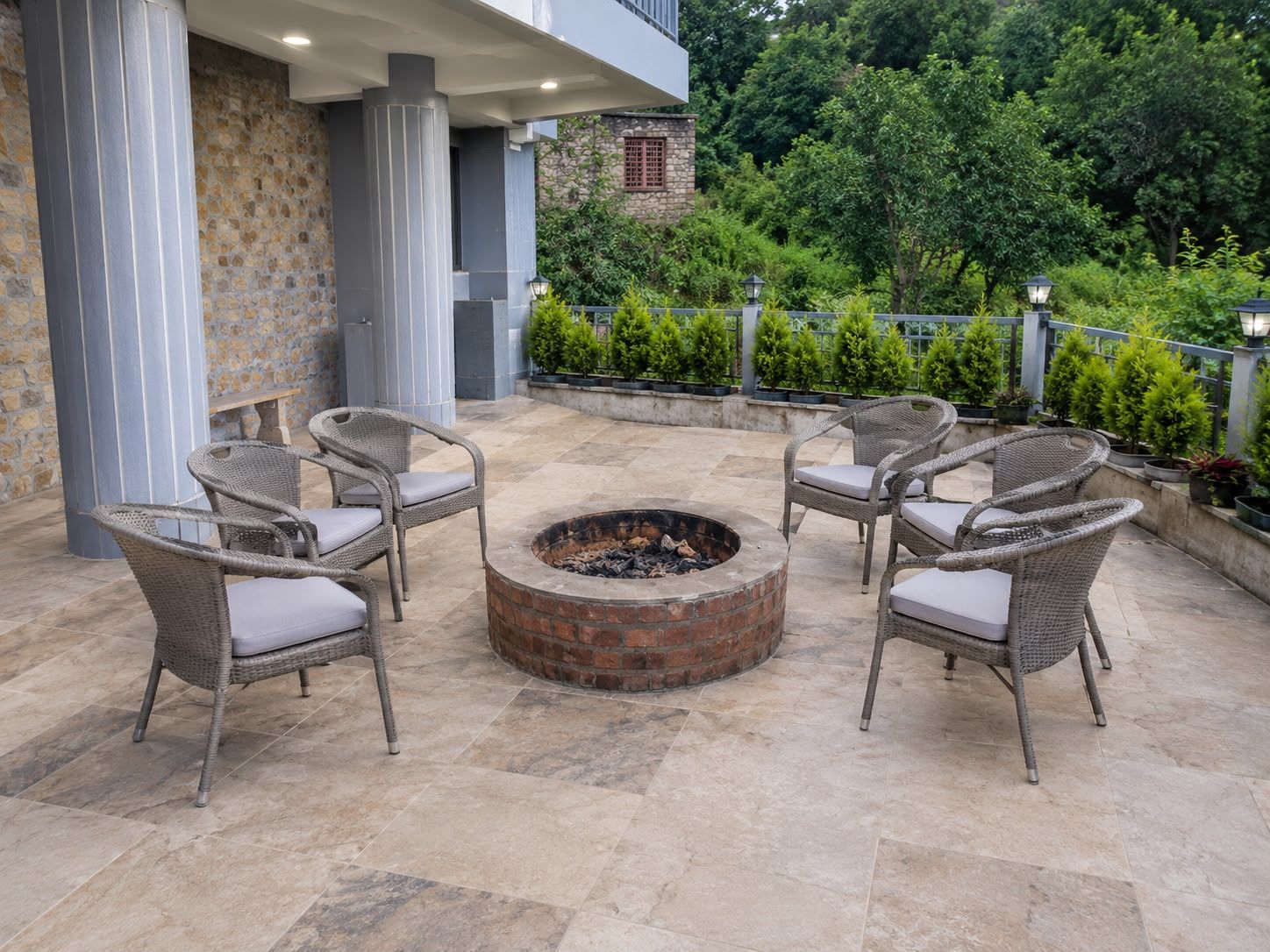 Un área de estar al aire libre con sillas de mimbre y una chimenea central.