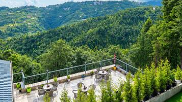 Una terraza con mobiliario exterior y vistas a un paisaje montañoso.