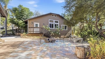 A house with a patio area featuring a stone floor, a wooden deck, and a small seating area with a table and chairs.