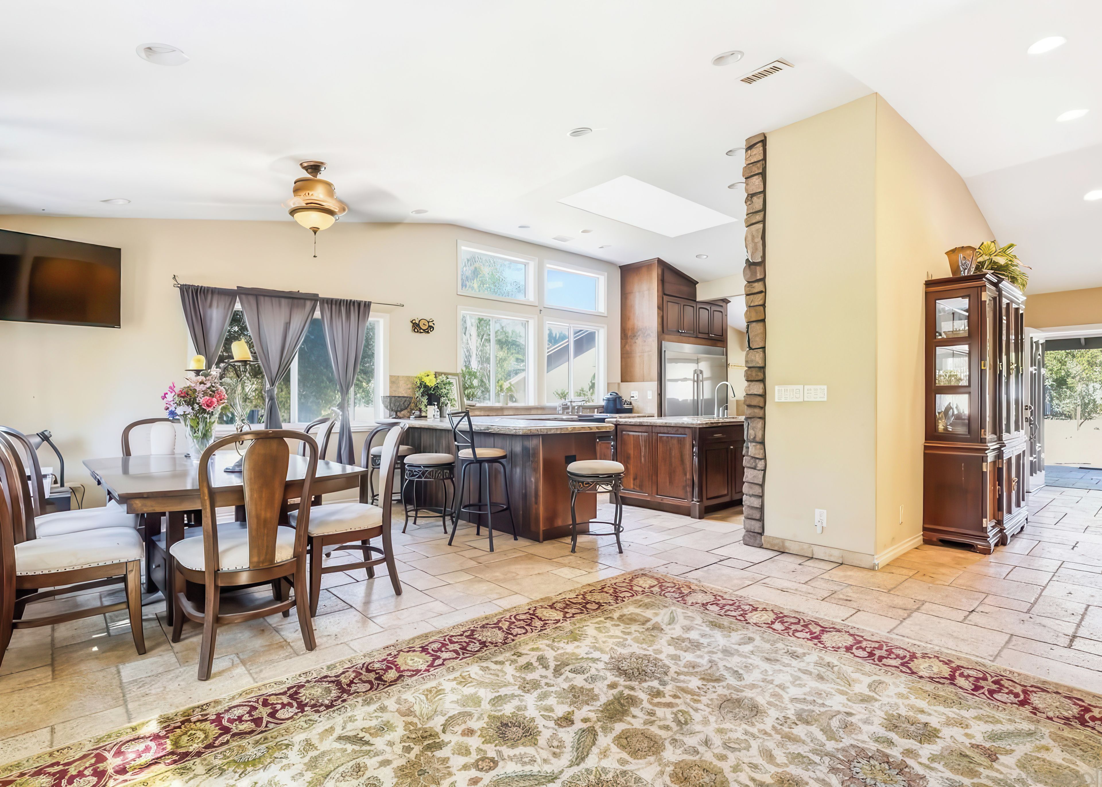 A modern kitchen with a central island, dining area with chairs, and a large rug.