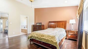 A bedroom with a wooden bed, a dresser, a nightstand, and a ceiling fan.