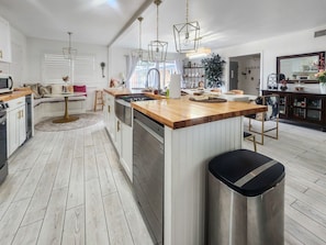 Una cocina moderna con una isla central, electrodomésticos de acero inoxidable e iluminación colgante.