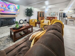 Una sala de estar con un sofá, una mesa de centro, un televisor y un comedor.