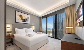 A modern hotel room with a large bed, bedside lamps, a city view, and a mounted TV. - Downtown Icon Living | Address Opera 3BR (Dubai)