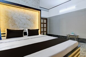 Habitación de hotel con una cama grande, cabecera de mármol, mesita de noche con botellas de agua y vistas al exterior.