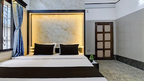 Ein Hotelzimmer mit einem Bett, einem Nachttisch, einer Wandleuchte, einer Tür und einem Fenster mit Vorhängen.