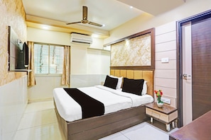 Ein Hotelzimmer mit Bett, Nachttisch und einem an der Wand befestigten Fernseher.