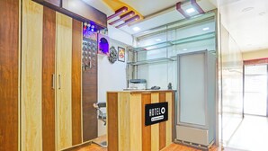 Un mostrador de recepción de hotel con detalles de madera, una vitrina de vidrio y un reloj fijado a la pared.