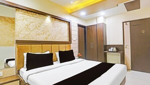Una habitación de hotel con una cama grande, un cabecero de madera, un armario y una mesita de noche con una tetera.