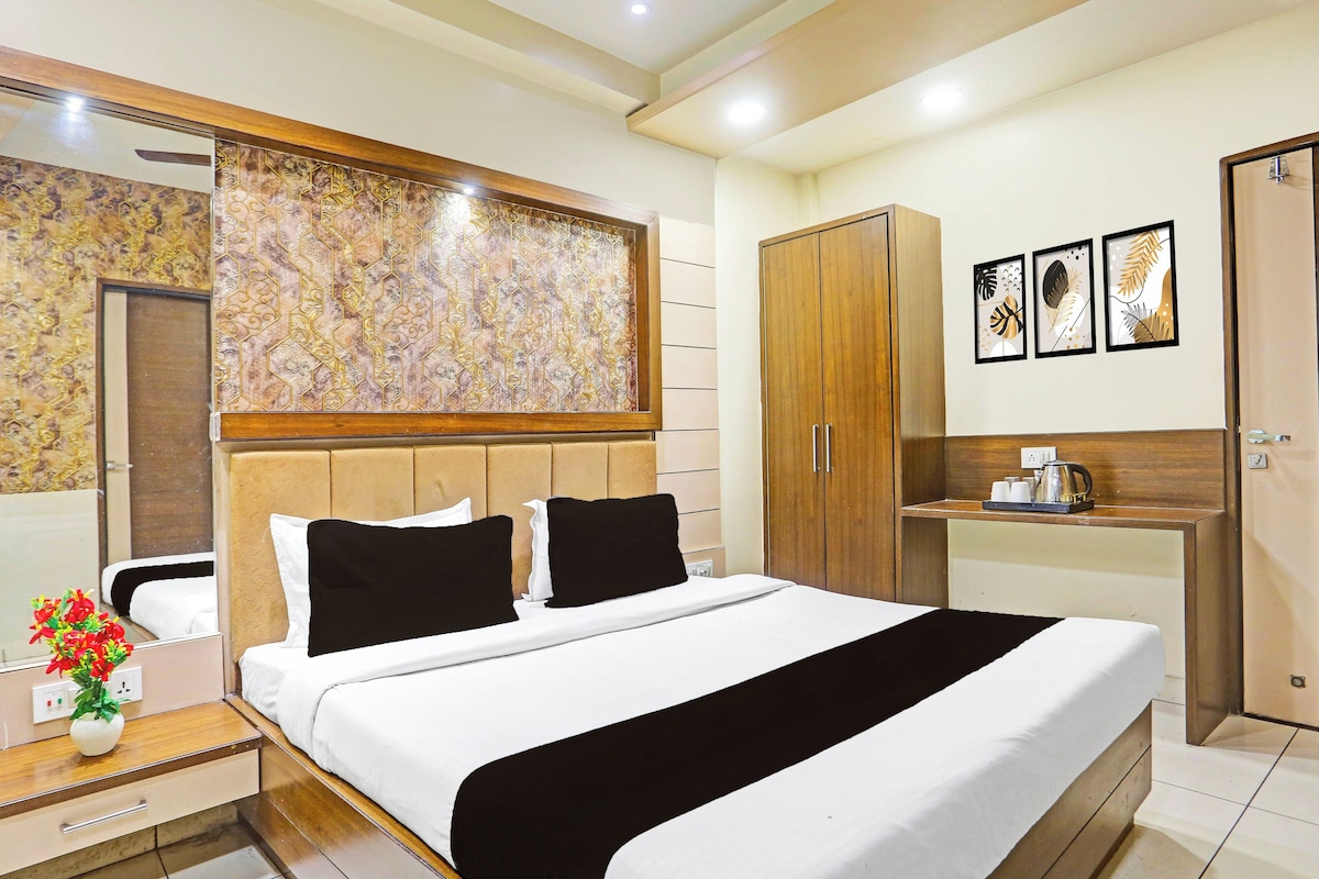 Ein Hotelzimmer mit Bett, Nachttisch, Spiegel, Kleiderschrank und einem kleinen Tisch mit Wasserkocher.