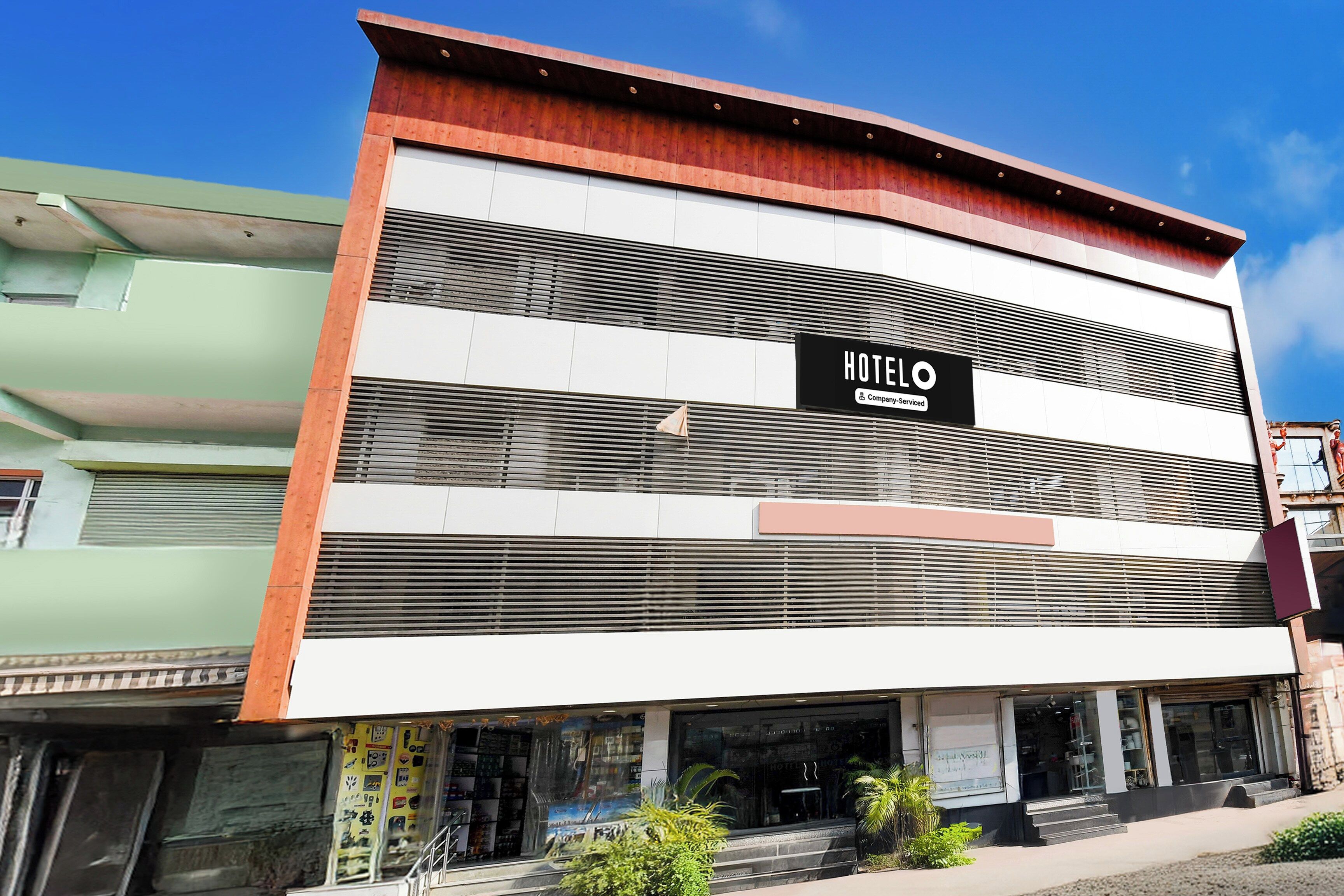 A modern hotel building with a prominent 'HOTEL' sign, a multi-story structure, and a visible entrance with steps leading up to the door.