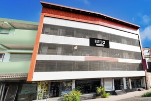 Un moderno edificio de hotel con un llamativo letrero que dice 'HOTEL', una estructura de varios pisos y una entrada visible con escalones que conducen a la puerta.