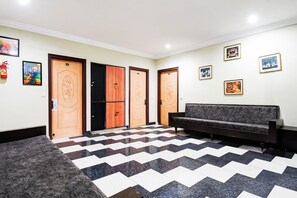 Un vestíbulo con piso a cuadros, un sofá y puertas numeradas.