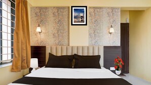 A hotel room with a large bed, two wall-mounted lamps, a framed picture above the bed, and a window with curtains. - Collection O Veerbhadra Nagar Baner (Pune)