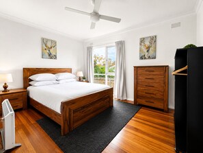 Ein Schlafzimmer mit einem hölzernen Bett, Nachttischen, einem Deckenventilator, einem Kleiderschrank und Kunstwerken an den Wänden.