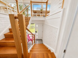 Eine Holztreppe mit Glastrennstreben führt zu einem Balkon mit Sitzgelegenheiten im Freien.
