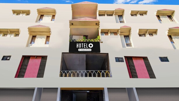 Ett hotell med en central entré, flera balkonger och en skylt som visar att det är ett hotell som tillhandahålls av ett företag.