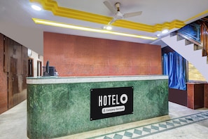 A hotel reception desk with a sign indicating it is company-serviced. - Hotel O Paradise Circle (Hyderabad)