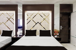 A hotel room with a large bed, dark wooden headboard, and a mirror. - Collection O Chidambaram Stadium (Chennai)