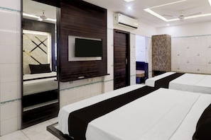 A hotel room with two beds, a flat-screen TV, an air conditioning unit, a ceiling fan, and a large mirror. - Collection O Chidambaram Stadium (Chennai)