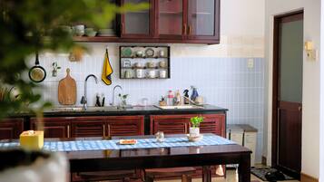 Uma cozinha com armários de madeira, painel de azulejos e uma mesa de jantar com toalha azul.