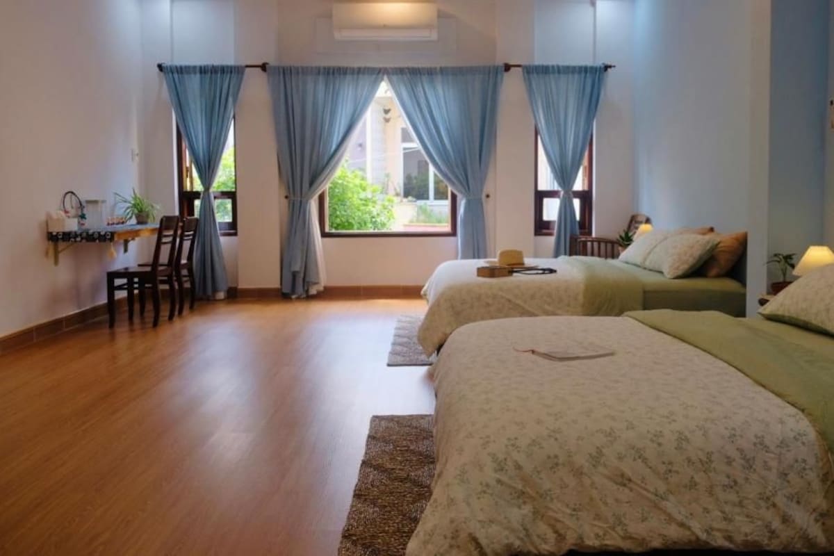 A hotel room with two beds, a desk, and a chair.