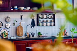A kitchen with wooden cabinets, a tiled backsplash, and various kitchen utensils and dishes. - Ruhome Quy Nhon - Central & Near Beach (Quy Nhon)