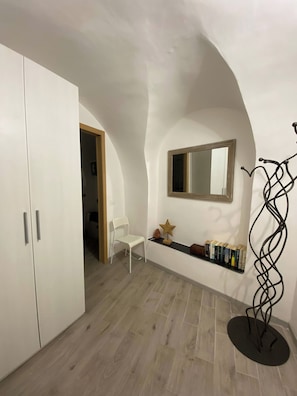 A room with a white wardrobe, a white chair, a shelf with books, a star-shaped decoration, and a mirror on the wall. - IL Viaggiatore House (Calice Ligure)