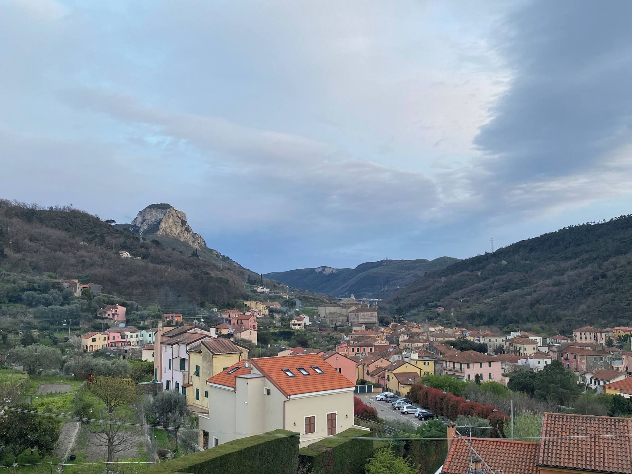 A hillside town with buildings, a prominent rock formation, and a clear sky.