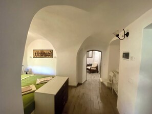 A narrow hallway with an arched ceiling leading to a bedroom with a bed and a nightstand. - IL Viaggiatore House (Calice Ligure)