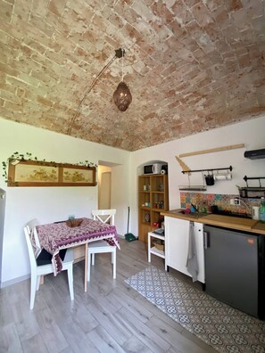 A kitchen with a brick ceiling, a dining table with chairs, a microwave, and a sink. - IL Viaggiatore House (Calice Ligure)