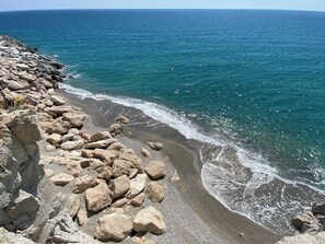 Eine felsige Küste mit brechenden Wellen am Strand.