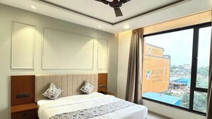 Una habitación de hotel moderna con una cama grande, un ventilador de techo y vistas a la ciudad desde la ventana.