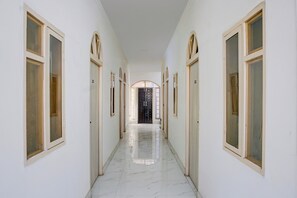 Un pasillo largo y estrecho con puertas a ambos lados, que conduce a una habitación oscura al final.
