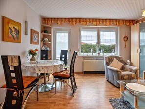 Un salón acogedor con zona de comedor, que incluye una mesa redonda, sillas, un sofá y una ventana con vistas.