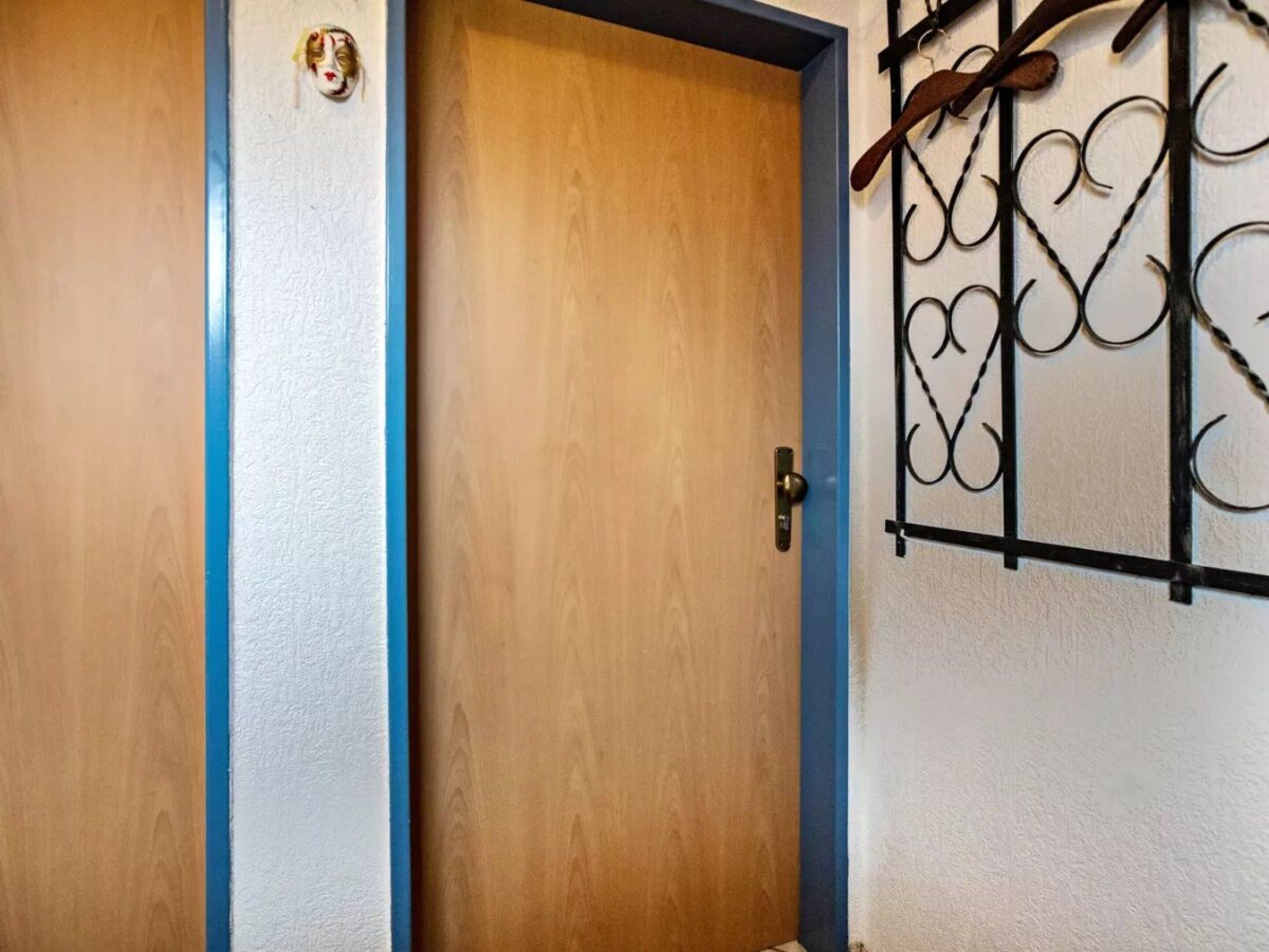A wooden door with a blue trim and a metal gate on the right side.
