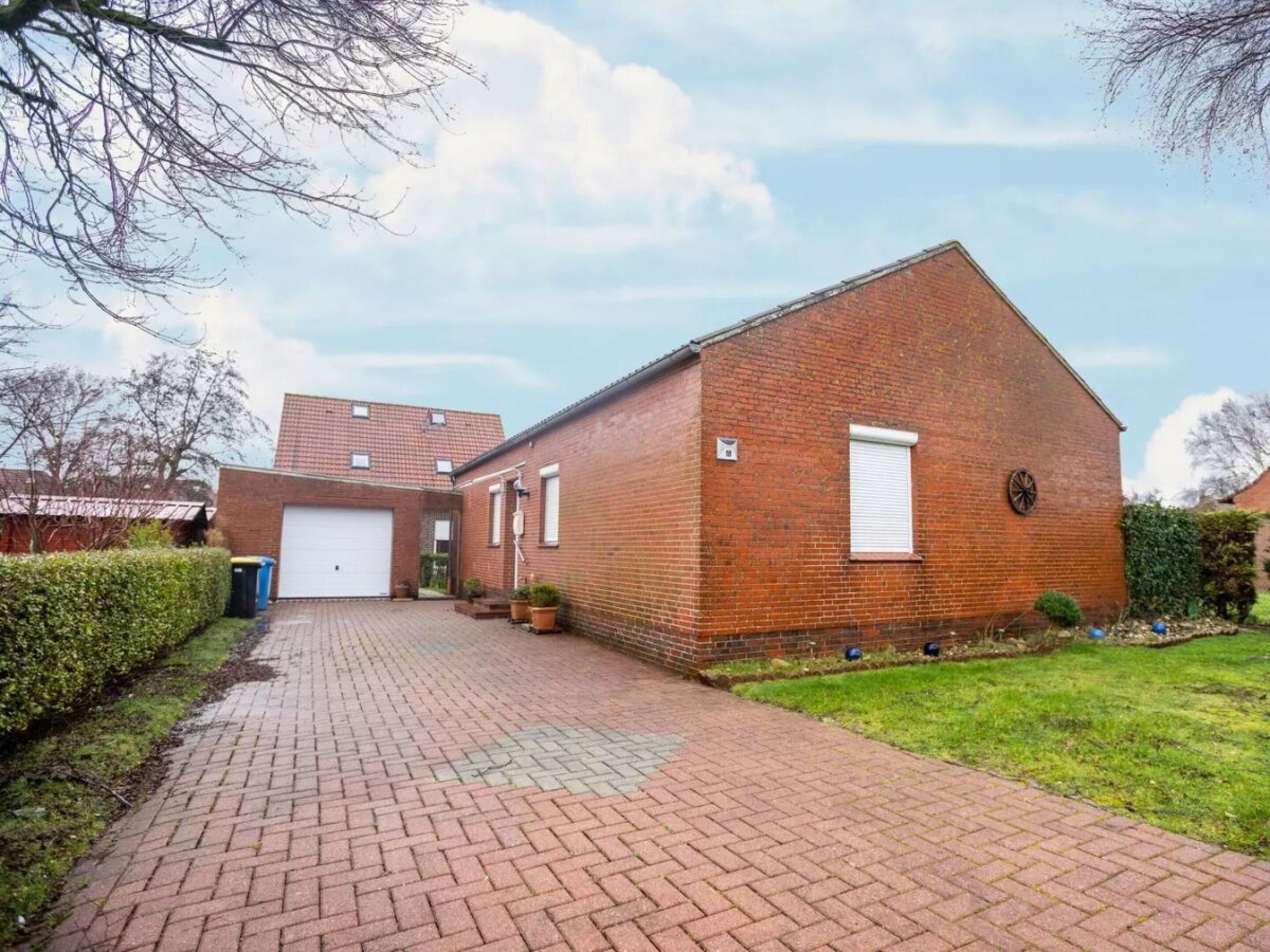 A brick building with a garage, a paved driveway, and a small lawn area.